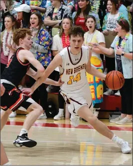  ?? Staff photo/Jason Alig ?? New Bremen’s Reece Busse (14) drives the baseline Friday night with the Cardinals student section watching in the background as New Bremen defeated Versailles in double overtime.