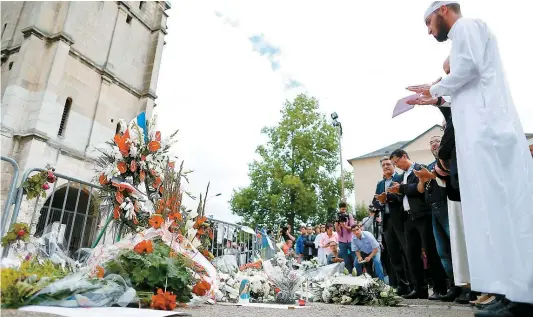  ??  ?? Des musulmans se sont recueillis, hier, devant l’église de Saint-Étienne-de-Rouvray où le prêtre catholique Jacques Hamel a été égorgé en pleine messe, mardi dernier, au cours d’une prise d’otages revendiqué­e par le groupe armé État islamique.