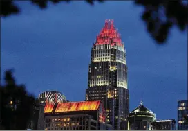  ?? JEFF SINER / THE CHARLOTTE OBSERVER ?? The Bank of America Corporate Center and The Carillon Building show support for the Charlotte Bobcats by having the tops of their buildings bathed in orange during a playoff game. Charlotte has seen an influx of young profession­als.