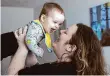  ?? Ellen M. Banner/Associated Press ?? Nicole Slemp, a new mother of 7-month-old William, lifts up her son in their home in Auburn, Wash. Slemp recently quit her job because she and her husband couldn’t find child care they could afford.