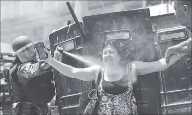  ??  ?? A Brazilian policeman sprays teargas against protestors. (Photo: EPA)