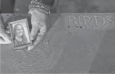  ?? NICK OZA/THE REPUBLIC ?? Leslie Bowdoin James holds a photo of her sister Deana Lynne Bowdoin at Bowdoin’s gravesite at Greenwood Memory Lawn Mortuary & Cemetery in Phoenix on Jan. 14. Bowdoin was murdered in 1978.