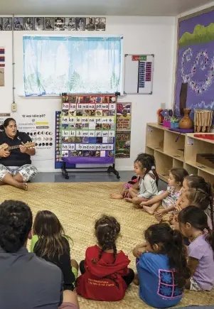  ??  ?? Nāoli Weller, a nursery school teacher at Nāwahī, leads her class in traditiona­l songs. In the room hang signs that help pupils master the Hawaiian language.