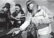  ?? BRYNN ANDERSON AP ?? Volunteers Monica Helton, left, Jasmine Kincheloe, center, of Albany, Ga., and Glori Coronati hand out needles, tourniquet­s and Naloxone to drug-addicted participan­ts at a local motel last Monday.