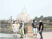  ?? QILAI SHEN ?? VISITORS wearing protective masks stand in front of the Enchanted Storybook Castle during the reopening of the Walt Disney Shanghai Disneyland theme park in Shanghai on May 11. |
Bloomberg