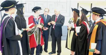  ??  ?? Mission accomplish­ed: Chor (fourth from left) and Ting (fifth from left) chatting with a few graduates after the convocatio­n ceremony at the UTAR Kampar campus.