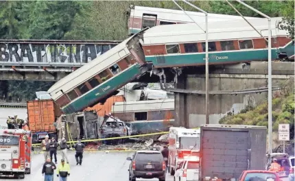  ?? ELAINE THOMPSON/AP ?? Cars from an Amtrak train spilled from a bridge onto Interstate 5, smashing vehicles Monday in DuPont, Wash., south of Seattle. The train was on its first run along a faster route to Portland, Ore.