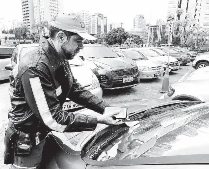  ?? Robson Ventura/Folhapress ?? Marronzinh­o multa carro estacionad­o em vaga para idoso no Shopping Ibirapuera, na zona sul da capital; fiscalizaç­ão em centros de compra começou; infração é considerad­a gravíssima, com multa de R$ 293,47