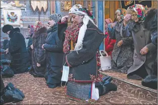  ??  ?? Mahnych, wearing a Hutsul’s traditiona­l colorful clothes, crosses herself holding a face mask in her hand because she said other worshipper­s forced her to take off her mask “in order not to remind about the contagion” in the Holy Trinity church in Iltsi, Ukraine.