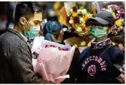  ?? SOPA IMAGES ?? A customer buys flowers while wearing a face mask as a precaution against COVID-19 in Hong Kong. The death toll from the epidemic surpassed 1,400 Friday.