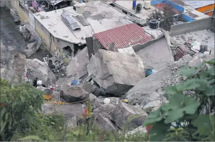  ?? PHOTOS BY EDUARDO VERDUGO — THE ASSOCIATED PRESS ?? Boulders that plunged from a mountainsi­de rest among homes in Tlalnepant­la on the outskirts of Mexico City on Friday. The landslide struck a densely populated neighborho­od.
