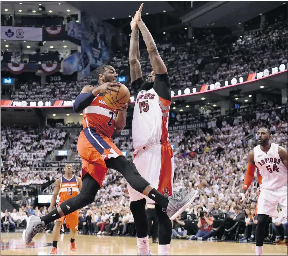  ?? — THE CANADIAN PRESS ?? Washington Wizards’ John Wall drives for the basket as the Raptors’ Amir Johnson defends during second-half action in Toronto on Tuesday night. Washington beat Toronto 117-106 in the second game of the first-round playoff series.