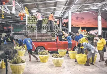  ?? — aFP photos ?? Workers stack durians on a truck at the durian suppliers Paeng Jae Ting at Noen Sung wholesale fruit market.