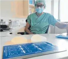  ?? FOTO: GABRIEL BOCK ?? Chirurg Oliver Lotter zeigt Brustimpla­ntate, die er Patientinn­en einsetzt. Rechts ein Implantat, dass eine natürliche Brust imitieren soll. Links ein rundes Implantat, das die Brüste natürlich nach oben pusht.