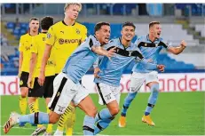  ?? FOTO: CORRADETTI/AP ?? Erling Haaland (links) schaut bedröppelt drein, während die Spieler von Lazio Rom eines ihrer Tore beim 3:1 gegen Dortmund bejubeln.