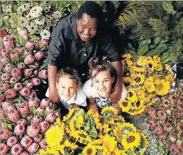  ?? Picture: EUGENE COETZEE ?? BEST OF THE BUNCH: Garden Gate Florist and Guest House in Port Elizabeth is preparing the flowers for Ironman through Interflora. Here, florist Beauty Windvoel is assisted by Jasmine Witthuhn, 8, left, and Bianca Crouse, 11, as she works on table...