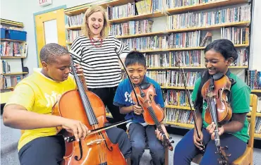  ?? DAN PEARCE METROLAND ?? Sistema executive director Christie Gray checks in on a group of students at St. Martin de Porres Catholic School.