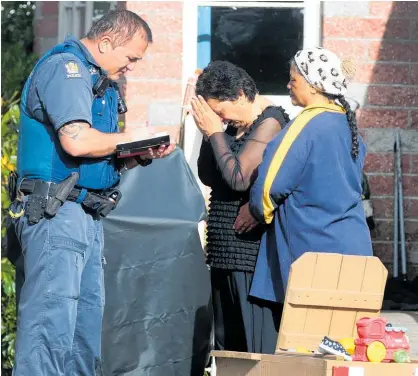  ??  ?? A police officer speaks with people believed to be family members of the toddler.