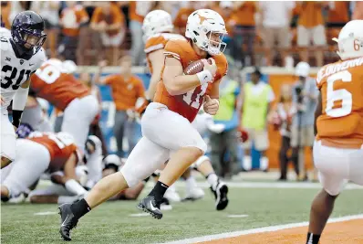  ?? AP Photo/Eric Gay ?? ■ Texas’ Sam Ehlinger (11) runs for a 2-yard touchdown against TCU during the second half Sept. 22 in Austin. Ehlinger has thrown for at least 200 yards and a touchdown in the first five games, becoming just the fourth Texas quarterbac­k to do that.