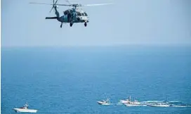  ?? JON GAMBRELL/AP 2018 ?? The U.S. Navy routinely has tense encounters with Iran’s Revolution­ary Guard. Above, a U.S. MH-60 Seahawk helicopter flies over Iranian patrol boats in the Strait of Hormuz.