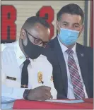  ??  ?? Delaware County Emergency Services Director Tim Boyce watches as Upper Darby’s new fire chief, Derrick Sawyer, signs on the dotted line.