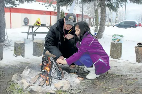  ?? ALLAN BENNER/STANDARD STAFF ?? Fred Bowering tends to a sacred fire at Niagara Regional Friendship Centre with Talise Lavalley, 9. Bowering kept the holiday fire going until Boxing Day, in memory of murdered and missing Indigenous women, as well as people struggling with mental...