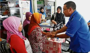  ??  ?? Doing his part: Azizul greeting traders at a hawker stall during a walkabout in Tanjong Datu.
