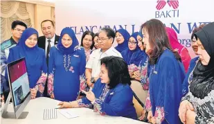  ?? — Gambar Bernama ?? PELANCARAN WEB BAKTI: Rosmah (duduk) melihat kandungan laman web selepas merasmikan laman web rasmi BAKTI pada majlis pelancaran laman web BAKTI dan setem ulang tahun ke-40 BAKTI di Seri Perdana di Putrajaya, semalam.