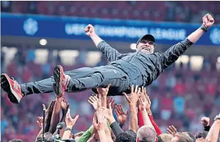  ?? Picture: Getty. ?? Liverpool manager Jurgen Klopp is thrown in the air by his players and staff during the celebratio­ns on the pitch.