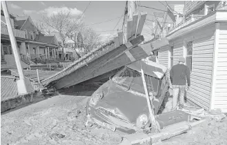  ?? Kathy Willens / Associated Press file ?? A car and part of a boardwalk washed into a street in the Rockaways neighborho­od of New York during Superstorm Sandy in 2012. The storm was cited in the city’s suit against five oil companies.