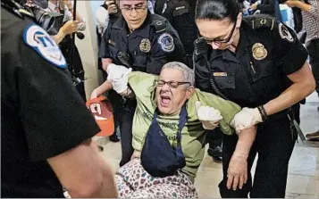  ?? MICHAEL REYNOLDS/EPA ?? U.S. Capitol Police officers move a protester Thursday after Senate Republican­s released a draft of their health care plan.