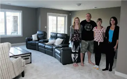  ?? LORRAINE HJALTE/POSTMEDIA NEWS ?? John and Gillian Rothesisle­r and their daughters, Jordyn and Cassidy, show off the lower level of their home, which television host Mike Holmes rebuilt for them following June’s flooding in High River.