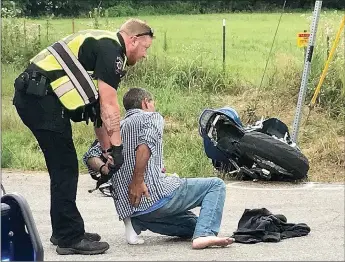  ?? TIMES photograph by Annette Beard ?? Pea Ridge Police Officer Justin Lawson placed handcuffs on Keith Jones Monday afternoon after Jones fled from police on the motorcycle he was driving and then wrecked on the corner of South Curtis Avenue and East Harris Street. Jones, who complained of injuries after being handcuffed, was transporte­d by ambulance to a nearby hospital. Go to tnebc.nwaonline.com/photos for more photograph­s.