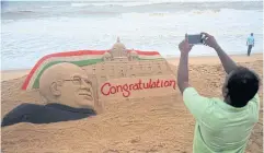  ?? AFP ?? An Indian man takes picture of a sand sculpture by artist Sudarsan Pattnaik depicting President-elect Ram Nath Kovind at a beach in Puri on Thursday.