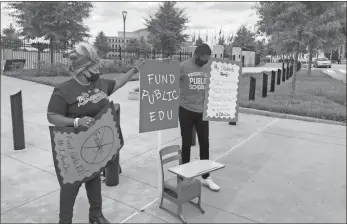  ?? Ap-jeff Amy ?? Justin Johnson, a middle school teacher in Chamblee, and Triana Arnold James, a Democratic state Senate candidate from Villa Rica, protest proposed state education budget cuts outside the Georgia state Capitol in Atlanta. The handful of protesters appeared on the same day a Senate committee voted to cut more than $1 billion in K-12 funding after state revenue nosedived because of the COVID-19 pandemic.