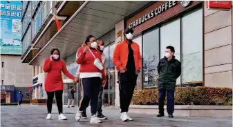  ??  ?? January 29, 2020: Several foreigners pass by a Starbucks store near Xuanwumen in downtown Beijing. Due to the novel coronaviru­s outbreak, almost everyone in the street wears a mask.