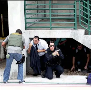  ?? AP/WILFREDO LEE ?? Law enforcemen­t officials shield civilians outside a garage at Fort Lauderdale-Hollywood Internatio­nal Airport in Fort Lauderdale, Fla., after gunfire broke out Friday.