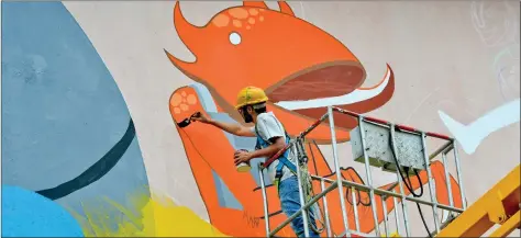  ??  ?? An artist from the Srishti School of Art, Design and Technology, perched atop a crane, paints the walls of the Peenya Metro Station as part of a work entitled ‘Art in Transit’ in Bangalore on Thursday. AFP