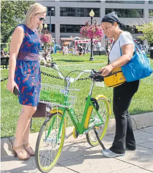  ?? AFP ?? Two women look at a LimeBike that is rented via an app in Farragut Square on Wednesday.