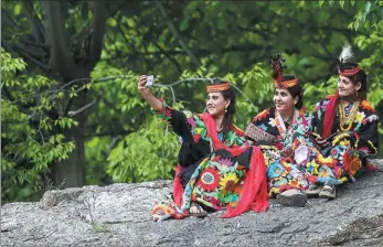  ?? AAMIR QURESHI / AGENCE FRANCE-PRESSE ?? A Kalash woman wearing a traditiona­l dress takes a selfie with her friends on May 16 during a break as they celebrate Joshi, a festival to welcome the arrival of spring, at Bumburate village in northern Pakistan.