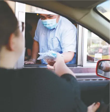  ?? GAVIN YOUNG ?? Free masks from the province to help in the fight against the coronaviru­s are handed out at a Mcdonald’s drive-thru on Wednesday.