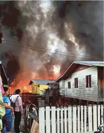  ??  ?? ORANG ramai melihat rumah terbakar di perkampung­an atas air di Kampung Pukat, Tanjung Batu Laut.