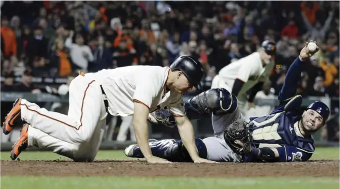  ?? — AP ?? SAN FRANCISCO: Milwaukee Brewers catcher Manny Pina, right, holds the ball for the home plate umpire to see after tagging out San Francisco Giants’ Nick Hundley, left, during the eighth inning of a baseball game Tuesday, in San Francisco.