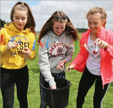  ??  ?? Hanna O’ Callaghan, Alison Dunlea and Laura Doody getting to grips with the Clothes Peg game at the Gaelic Sunday celebratio­n at Meelin GAA Grounds.