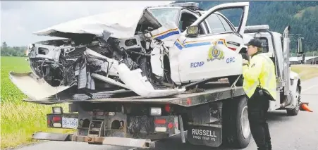  ??  ?? Abbotsford police Const. Rob Vroom examines a badly damaged RCMP cruiser in this undated photo.