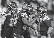  ?? Stephen Brashear / Associated Press ?? Seattle tight end Ed Dickson, center, celebrates with Russell Wilson, right, after the go-ahead touchdown.