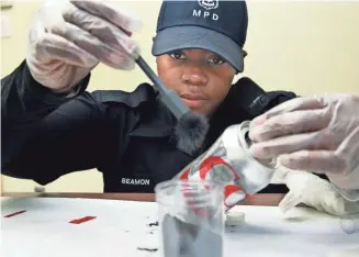  ?? ANGELA PETERSON / MILWAUKEE JOURNAL SENTINEL ?? Jennifer Beamon, a Milwaukee police recruit, dusts for fingerprin­ts at a mock burglary crime scene at the Milwaukee Police Academy. Her recruit class will graduate Thursday. See video at jsonline.com/news.