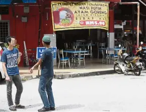  ??  ?? After a meal: Two customers standing outside a restaurant for a smoke in Kuantan. — Bernama