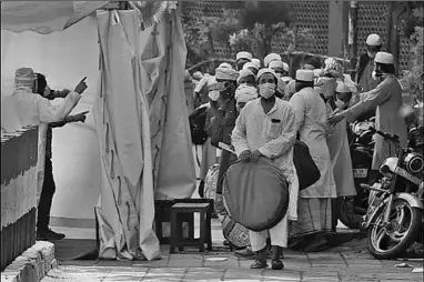  ??  ?? Indian paramedics check Tablighi Jamaat members before they were taken to a quarantine facility, in the Nizamuddin area of New Delhi. (Photo: Al Jazeera)