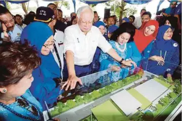 ??  ?? NAJIB dan Rosmah melihat model pelan Bangunan Permata Kurnia Zon Selatan di Taman Rumahku Syurgaku, Bukit Katil.